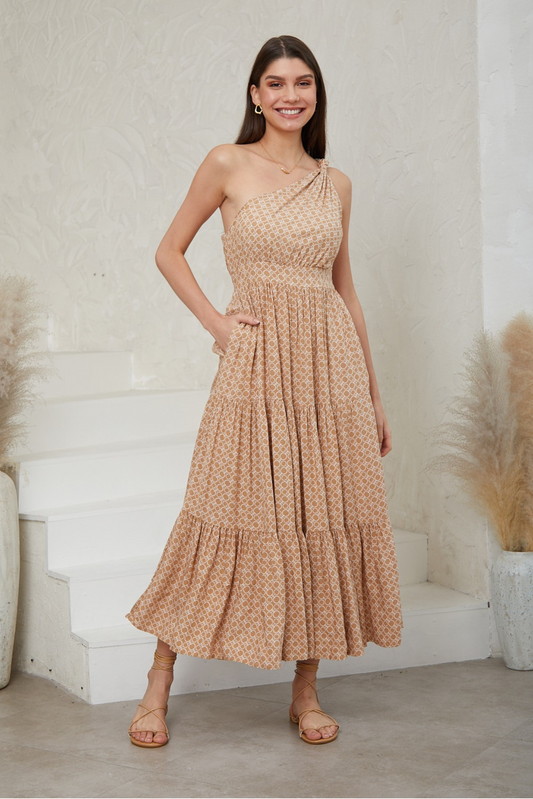 Smiling woman wearing Solara Boheme Amara One-Shoulder Maxi Dress in beige geometric print with tiered skirt and sandals