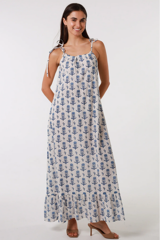 Woman wearing Solara Boheme Bloom Slip Maxi Dress in white with blue floral print and adjustable shoulder ties