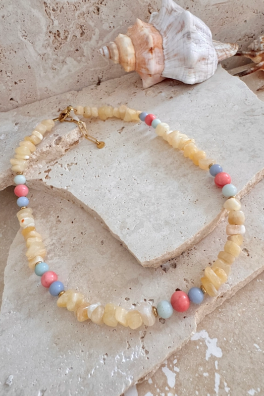 Necklace with multicolored beads on a textured surface with shells