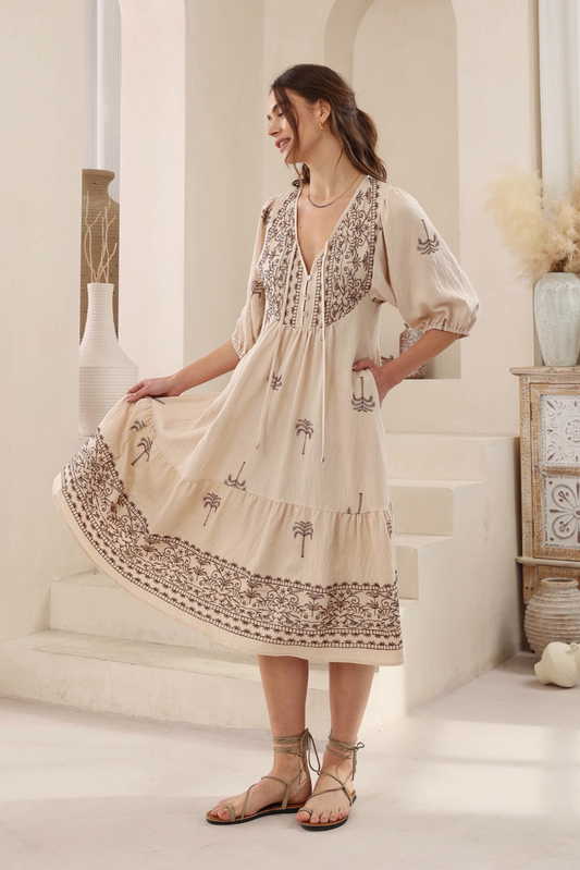 Woman wearing Solara Boheme Desert Palm Midi Dress with embroidered palm trees and 3/4 sleeves in a bright room