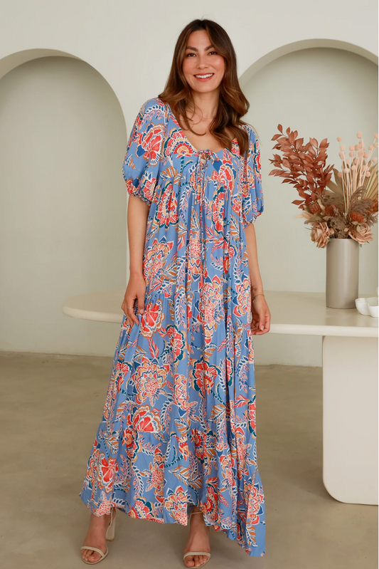 Woman wearing a Solara Boheme Elise Maxi Dress with floral rayon fabric and puff sleeves standing indoors smiling
