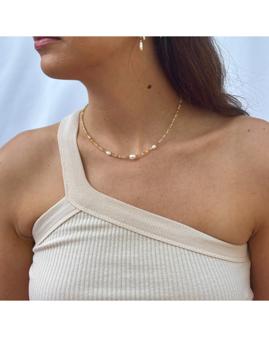 Woman wearing Exhale Necklace Pebbly Beach Gold with pearls and gold plated beads on a delicate chain