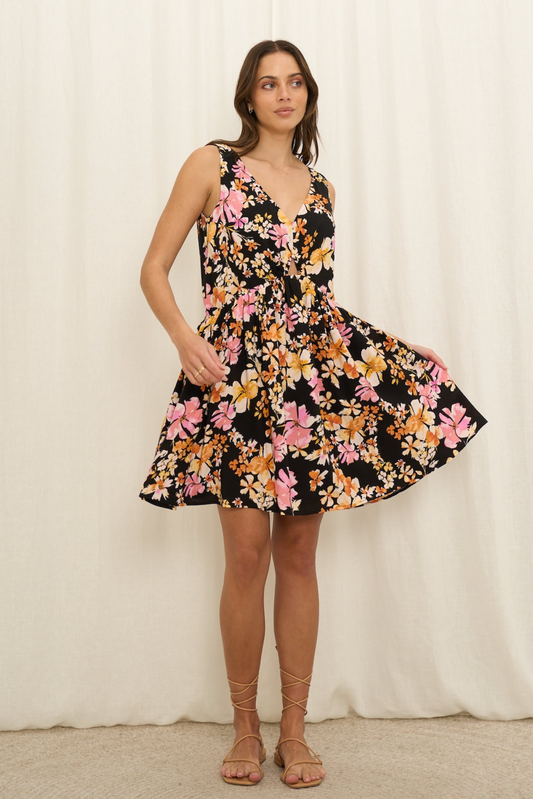 Model wearing Leilani Mini Dress by Solara Boheme with floral print, V-neckline, and flowy A-line skirt in black base.