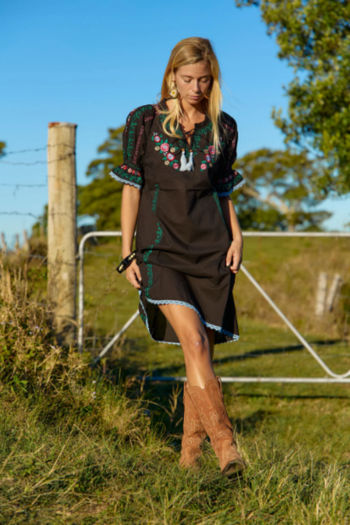 Woman wearing Spell Mini Dress by Solara Boheme with floral embroidery and bohemian style outdoors in sunlight
