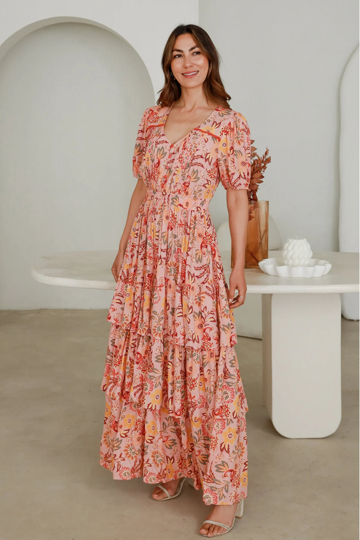Woman wearing a Solara Boheme Vera Maxi Dress with floral print and tiered design in a bright indoor setting