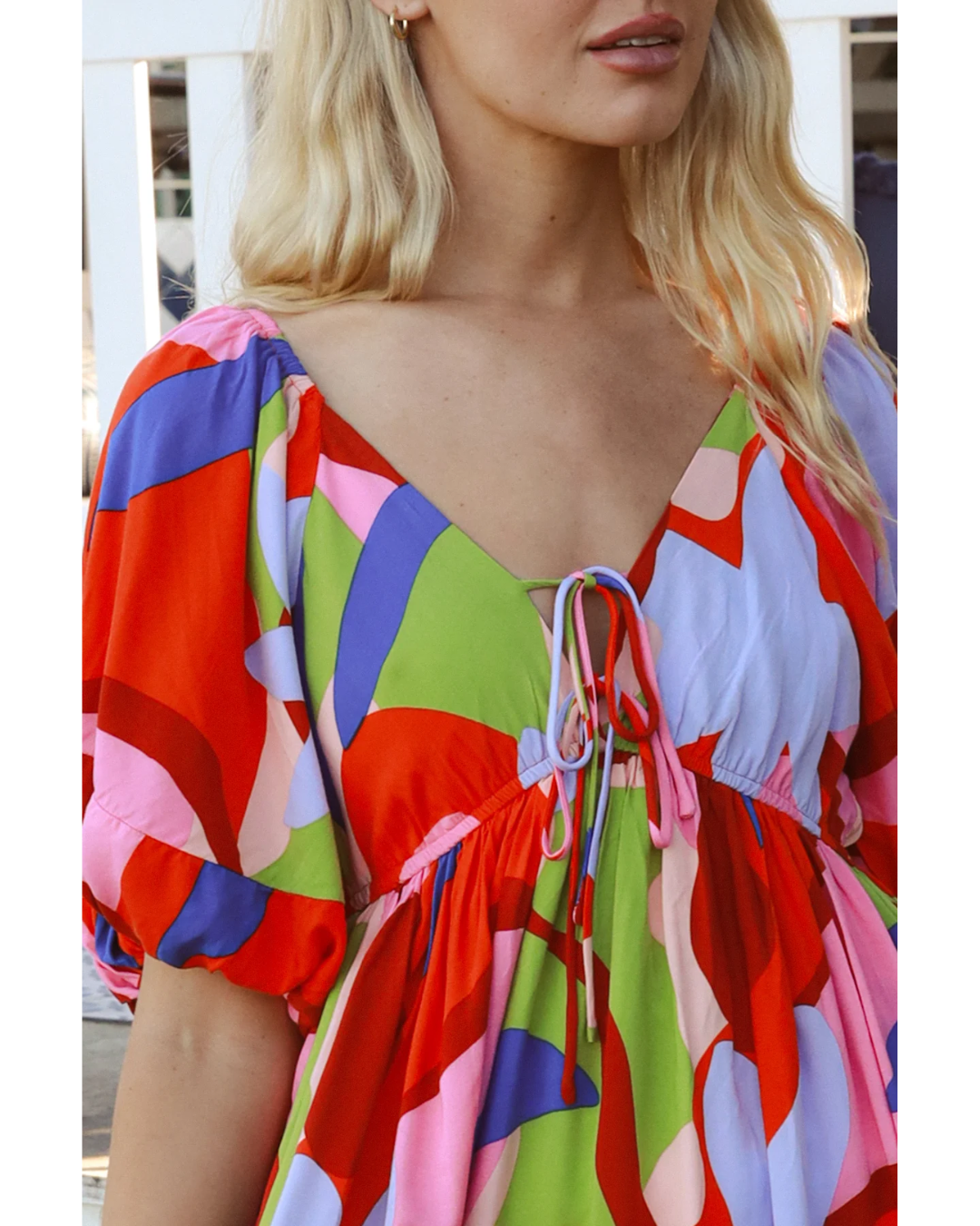 Close-up of a colorful Alberta Mini Dress with bold abstract print and puffed sleeves on a model
