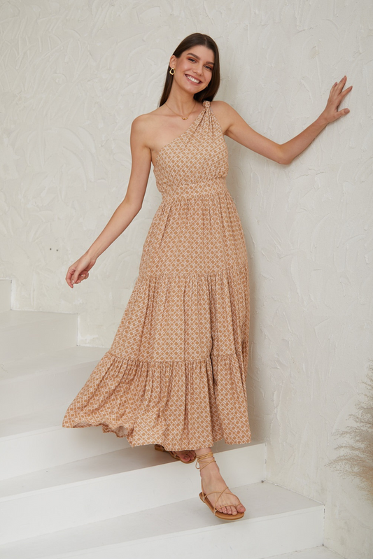 Smiling woman wearing Solara Boheme Amara One-Shoulder Maxi Dress with beige geometric print on white stairs