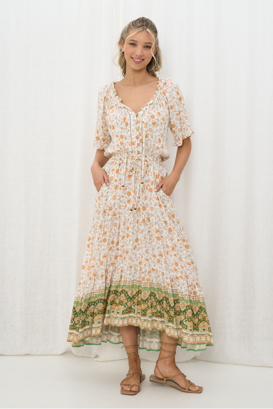 Smiling model wears Amber Bloom Maxi Dress by Solara Boheme with floral print and green border hem in soft flowing fabric