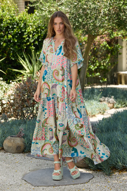 Woman wearing colorful Amisha Marbella Maxi Dress by Solara Boheme in garden setting with flowing tiers and relaxed sleeves