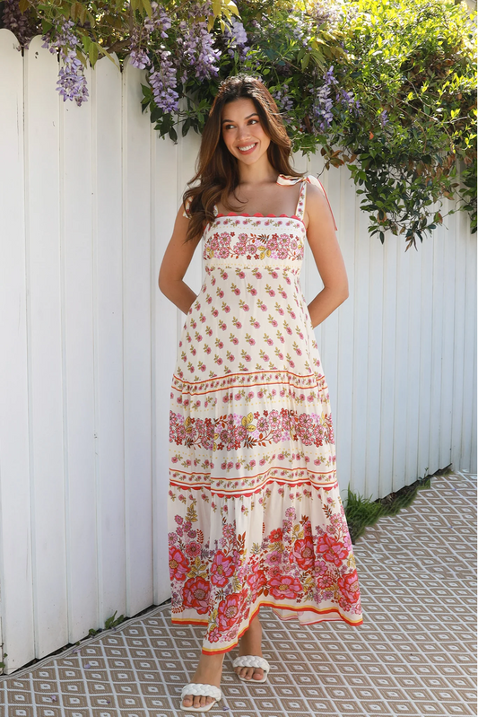 Woman wearing the Ariah Slip Maxi Dress by Solara Boheme with floral print and adjustable shoulder ties outdoors