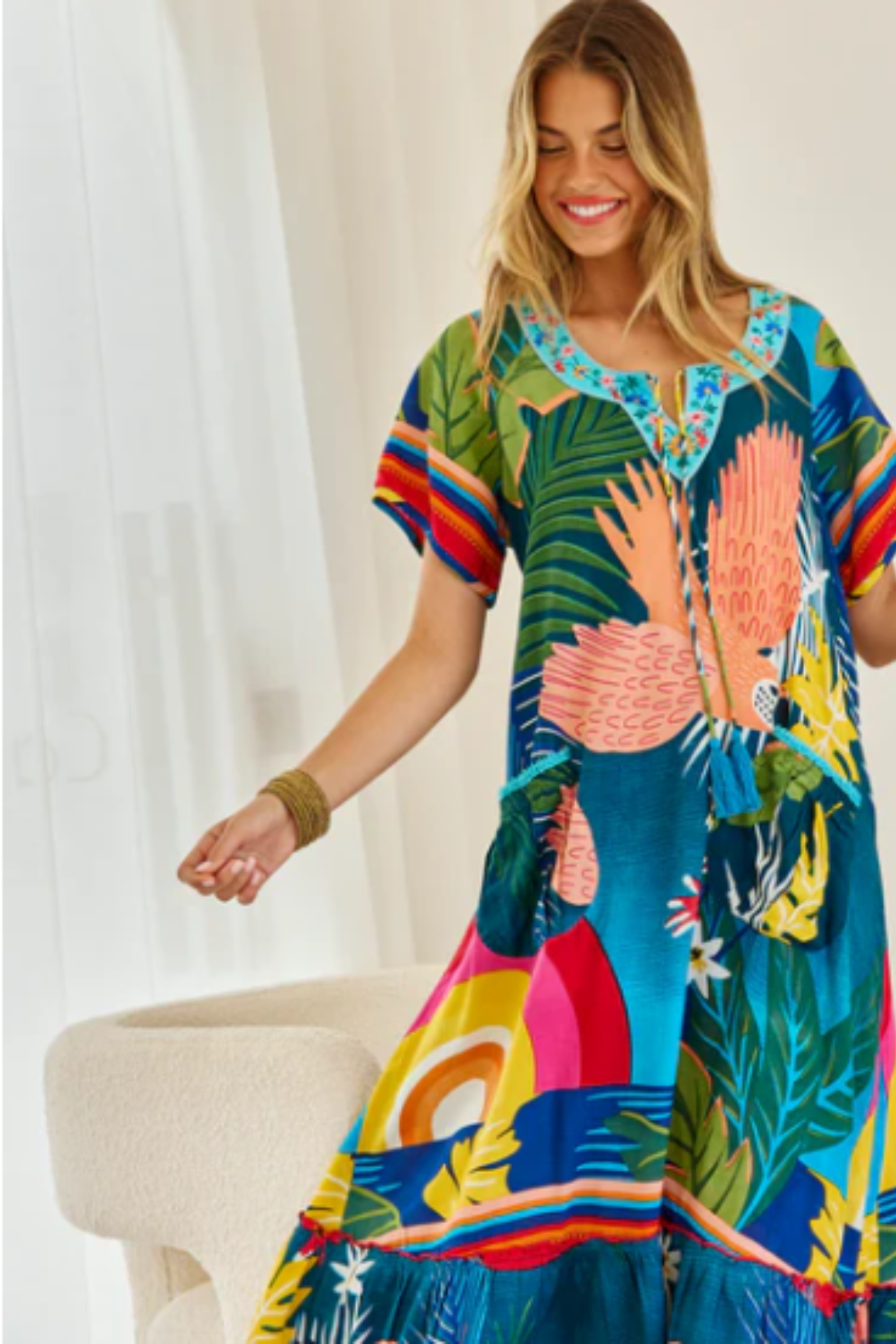 Colorful Boojee Maxi Dress by Solara Boheme with embroidered neckline and tropical print worn by smiling woman indoors