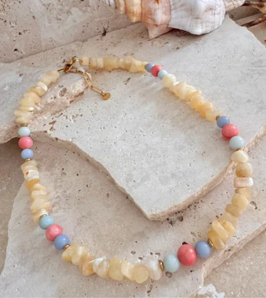 Necklace with pastel beads on a stone surface with shells