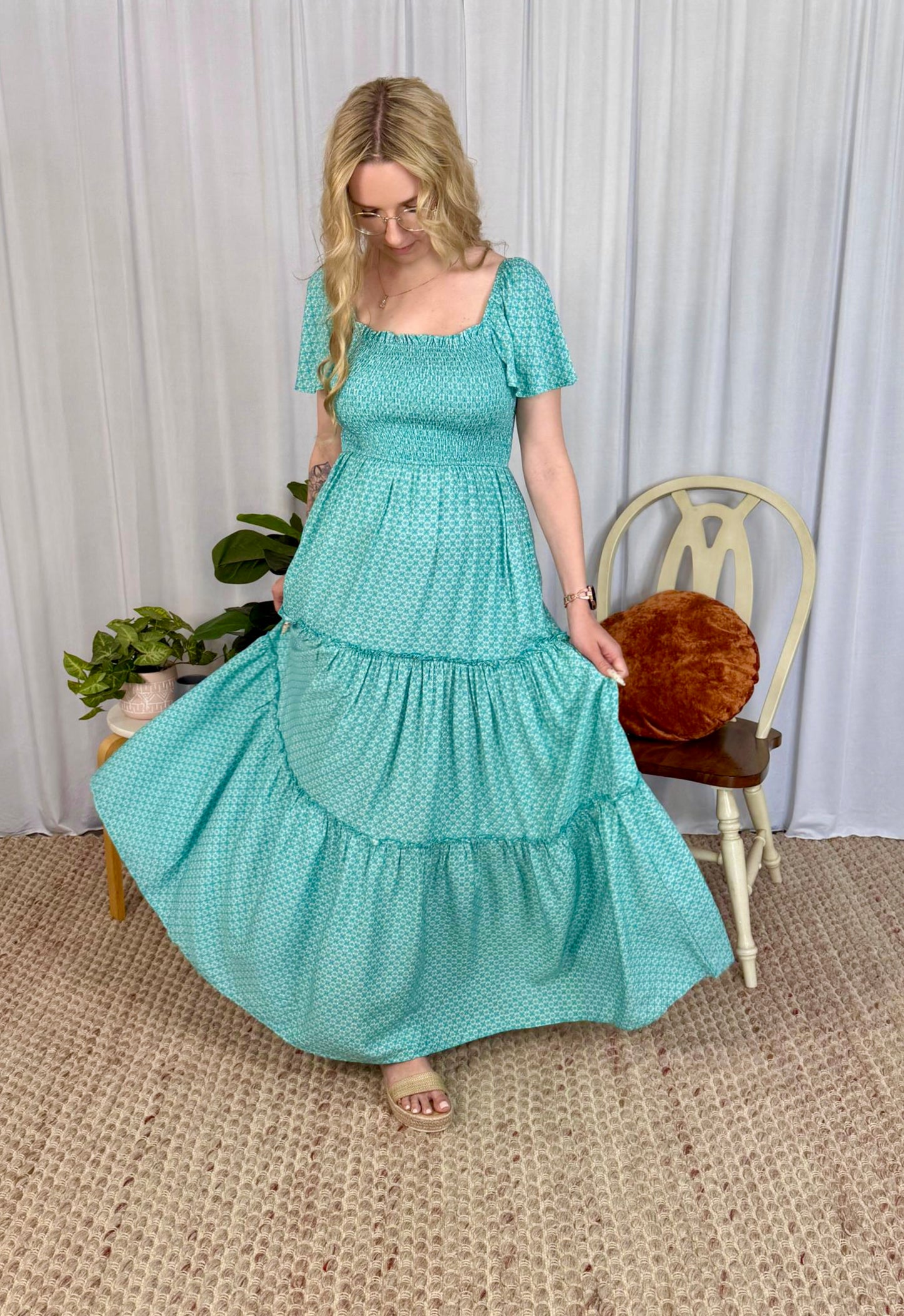 Woman wearing Solara Boheme Elsie Maxi Dress in aqua with smocked bodice and tiered skirt twirling indoors