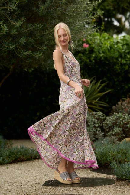 Woman wearing Solara Boheme Esme Maxi Dress in floral cotton fabric with pink trim outdoors in garden setting