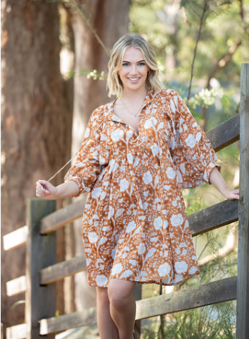 Woman outdoors wearing Solara Boheme Fleur Mini Dress in earthy brown with floral print and billowy sleeves