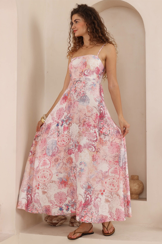 Woman wearing a floral dress standing against a neutral wall.