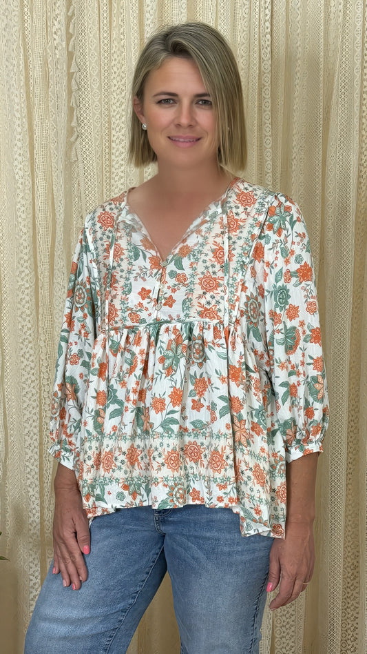 Woman wearing Solara Boheme Harvest Blossom Blouse with orange green floral print and relaxed fit style