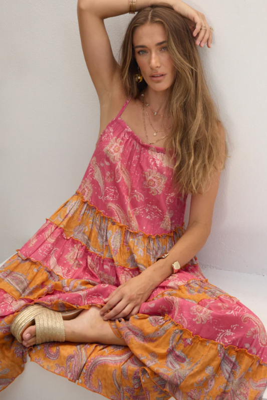 Woman wearing a pink and orange paisley Hip Hop Midi Dress by Solara Boheme with delicate straps and tiered flowy design