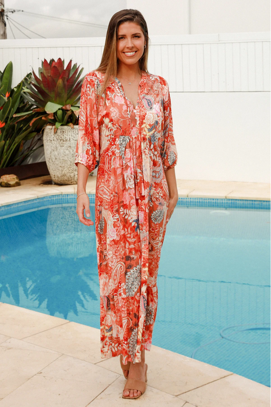 Smiling woman wearing Solara Boheme Jaylani Midi Dress with vibrant pattern standing by poolside outdoors