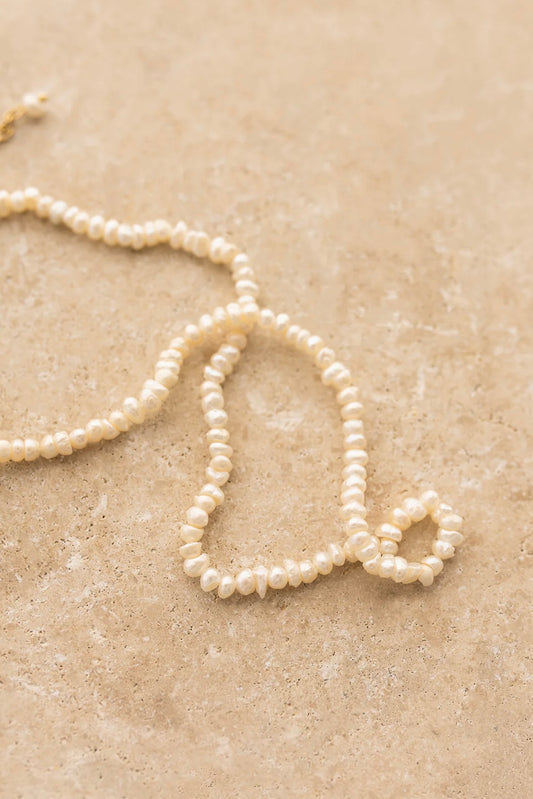Kaia Necklace by My Store featuring delicate freshwater pearls on a textured beige surface for elegant style.