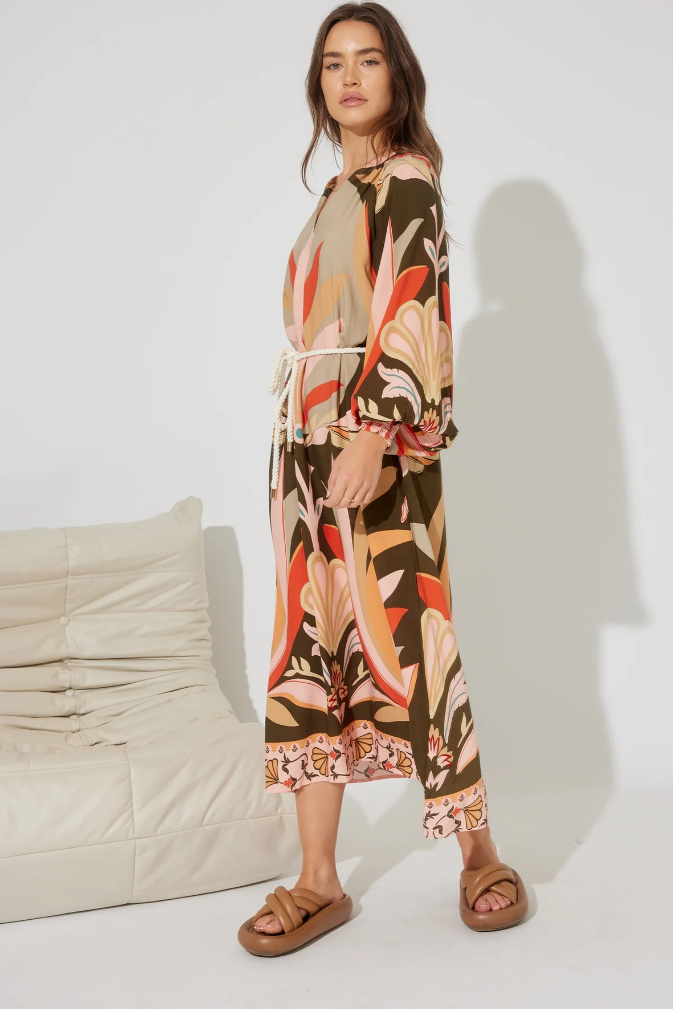 Woman wearing Solara Boheme Koa Maxi Dress with vibrant floral print and rope tie belt in relaxed setting