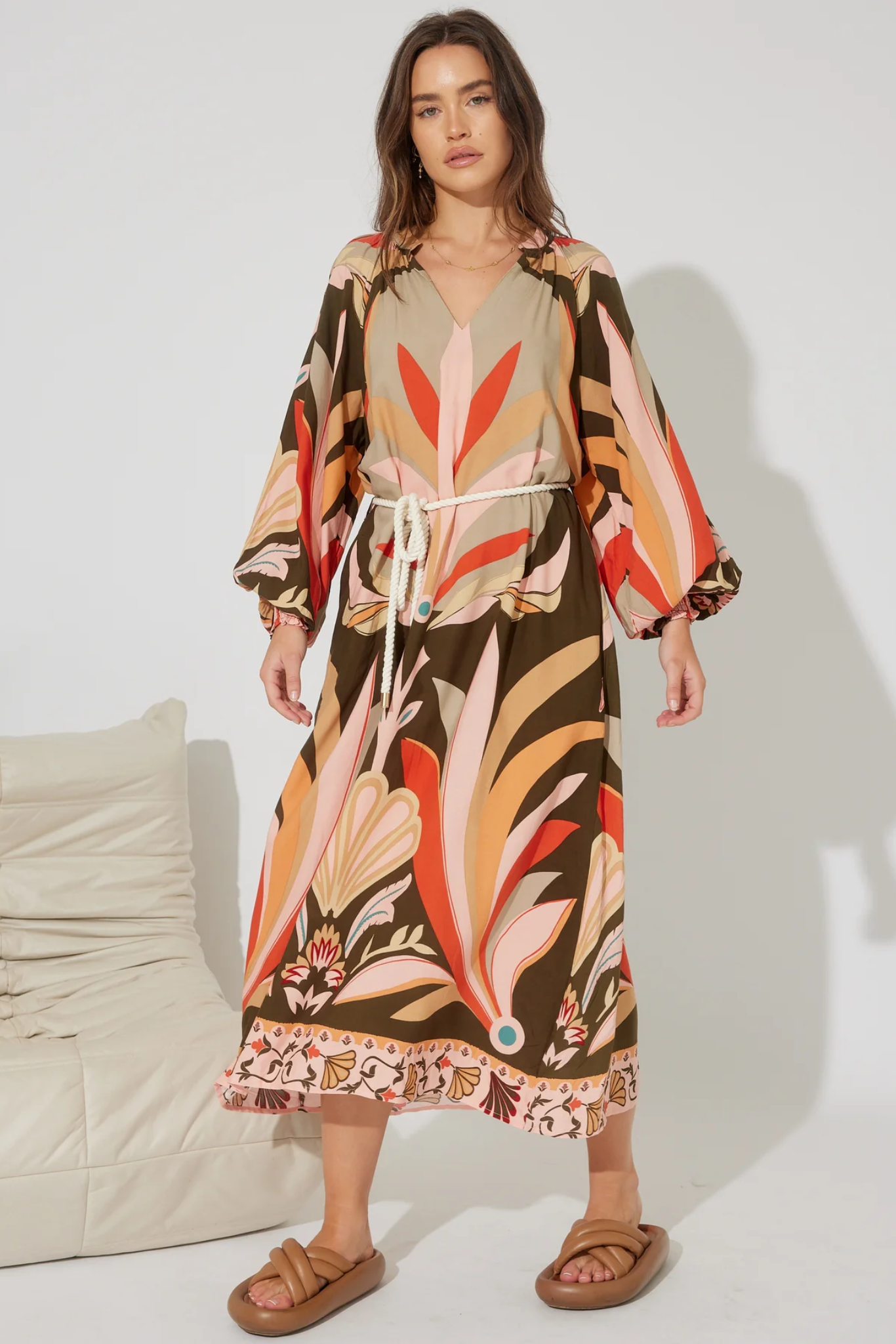 Woman wearing Solara Boheme Koa Maxi Dress with colorful print, rope tie belt, and long sleeves in a bright setting