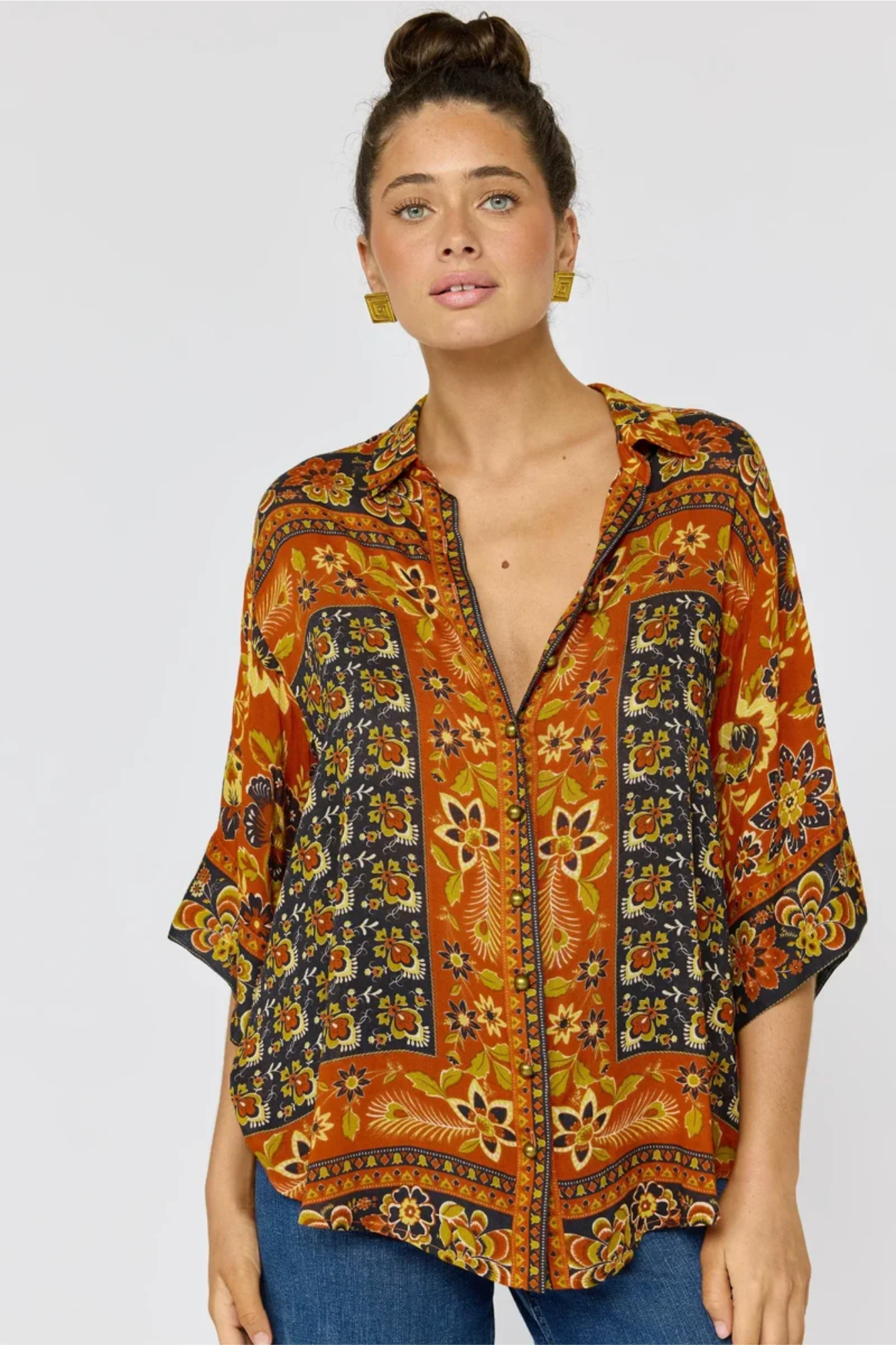 Woman wearing a patterned orange and black blouse on a white background
