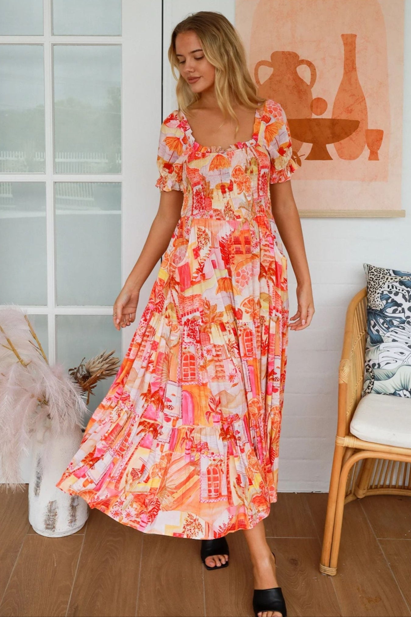 Woman wearing colorful Maribel Maxi Dress from My Store standing indoors by window and chair