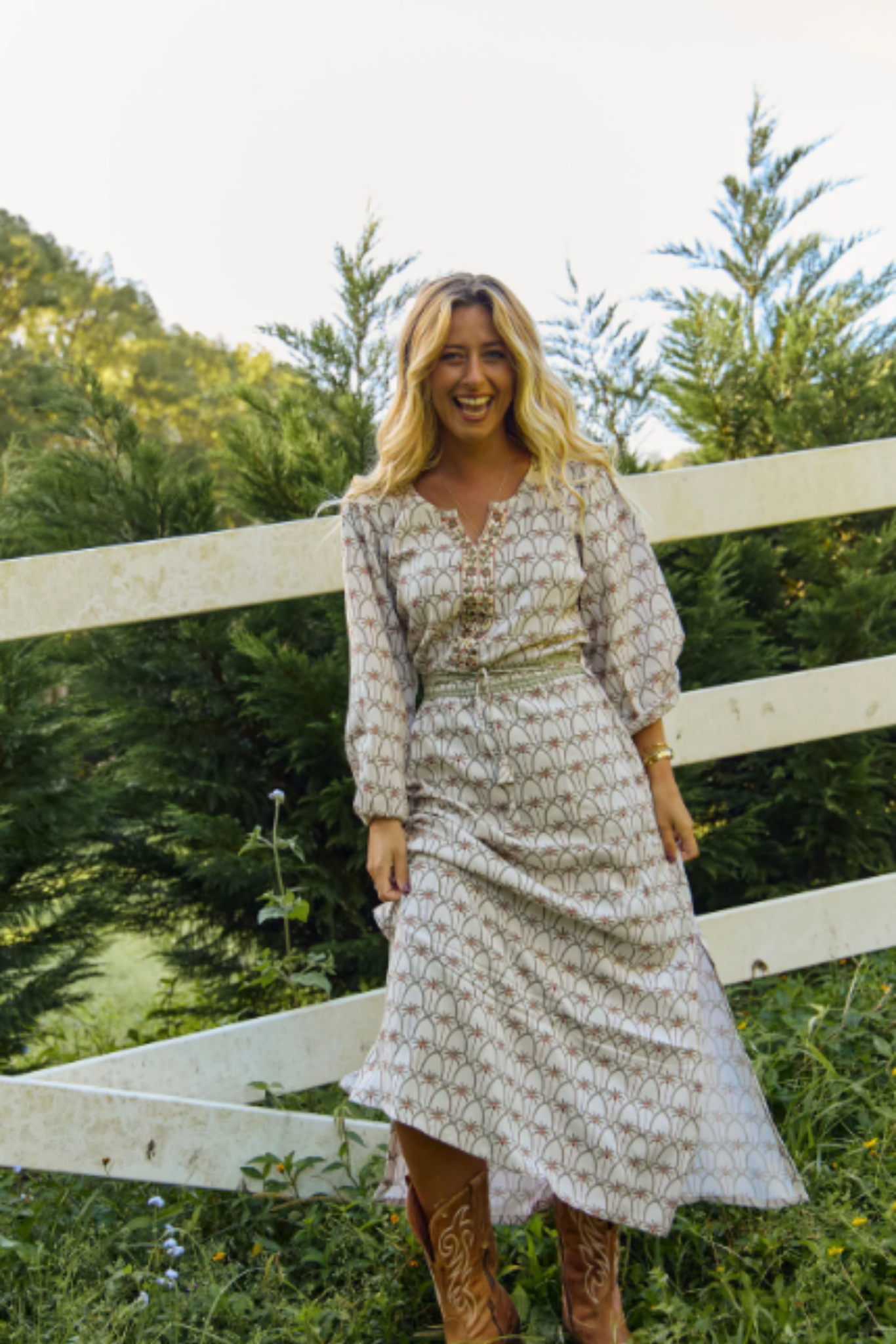 Woman smiling outdoors wearing Solara Boheme Palm Springs Maxi Dress with nature-inspired print and long sleeves