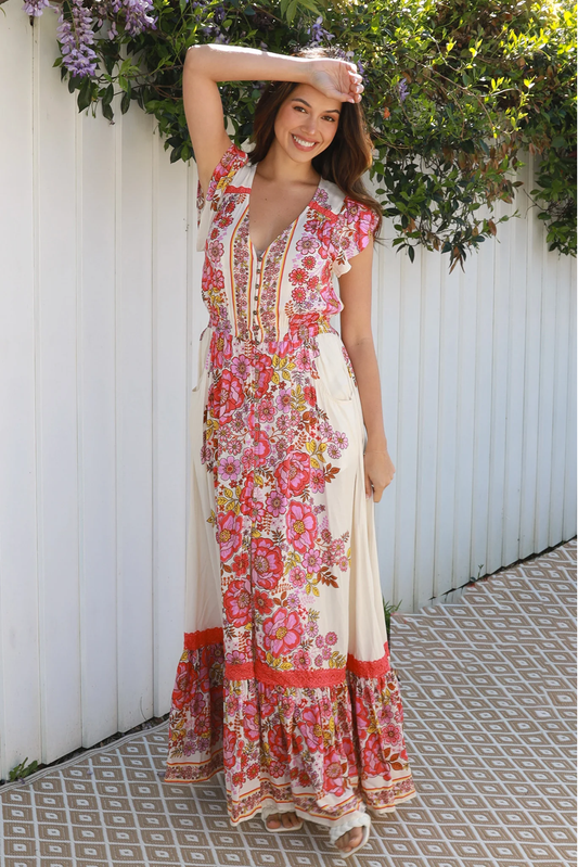 Woman wearing Rosalie Maxi Dress by Solara Boheme with vibrant floral print and flutter sleeves outdoors