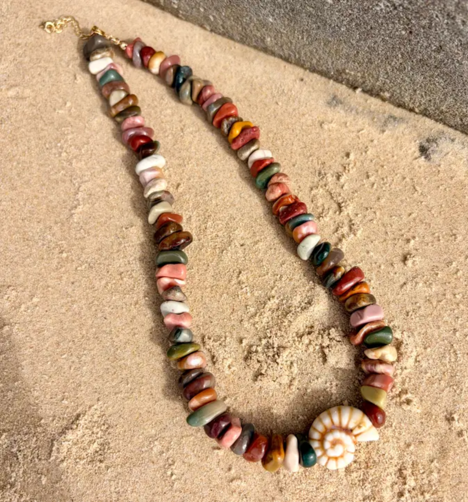 Colorful stone necklace on a sandy surface