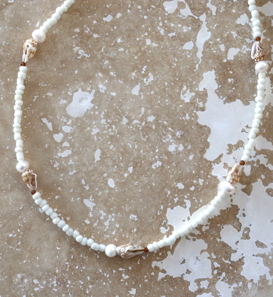 Necklace with white beads on a textured beige surface