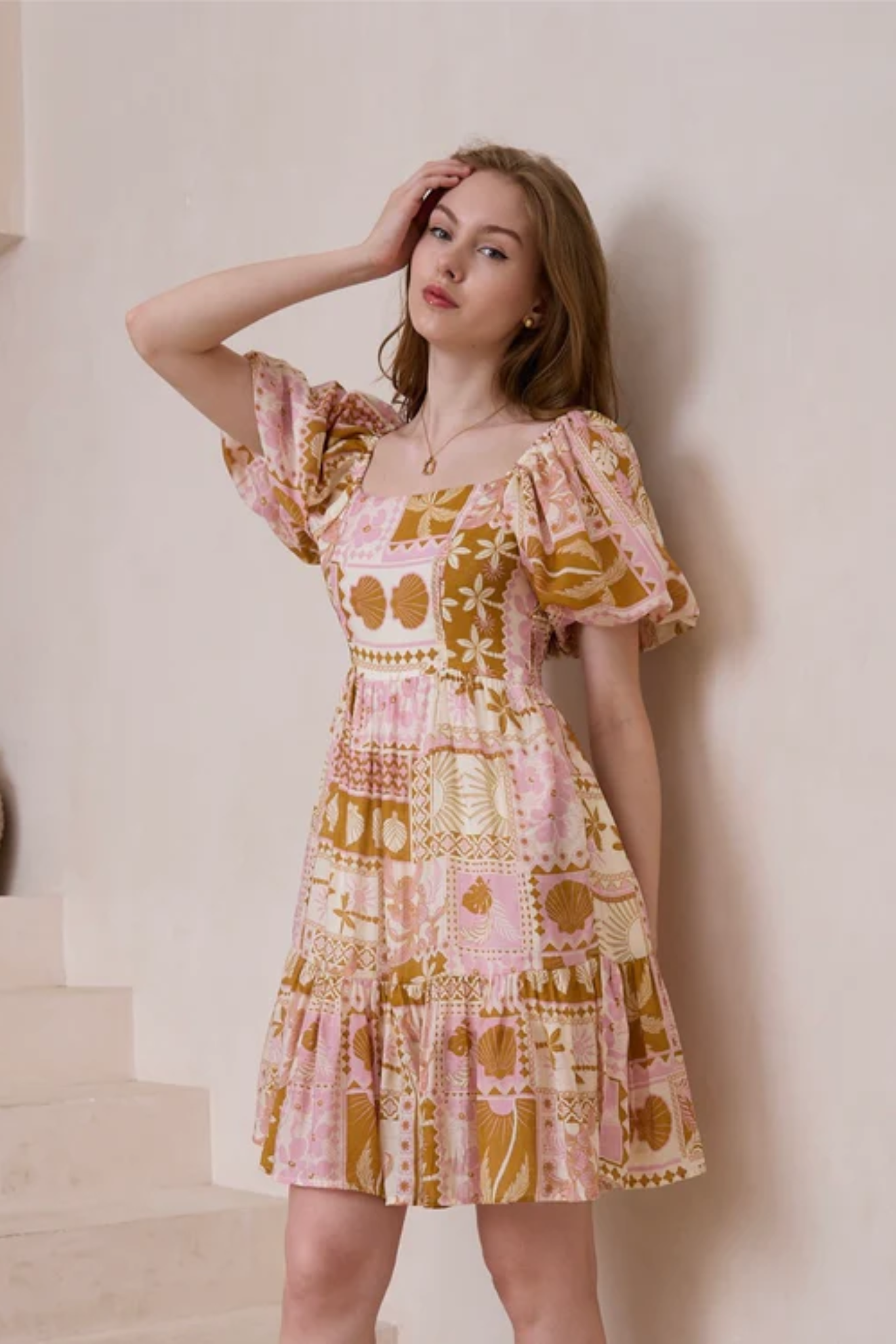 Woman in pink and mustard patterned Shelley Mini Dress by Solara Boheme with square neckline and puff sleeves