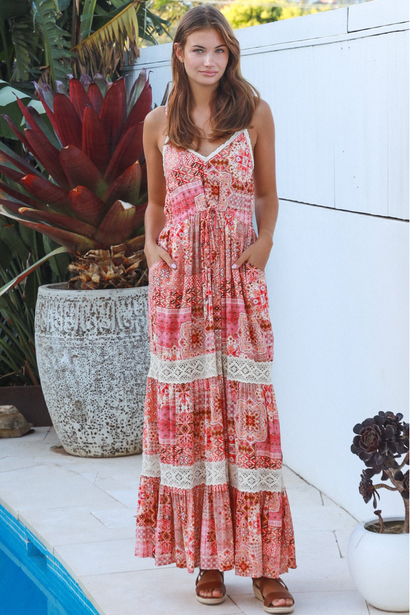 Woman in a floral dress standing by a pool with plants around