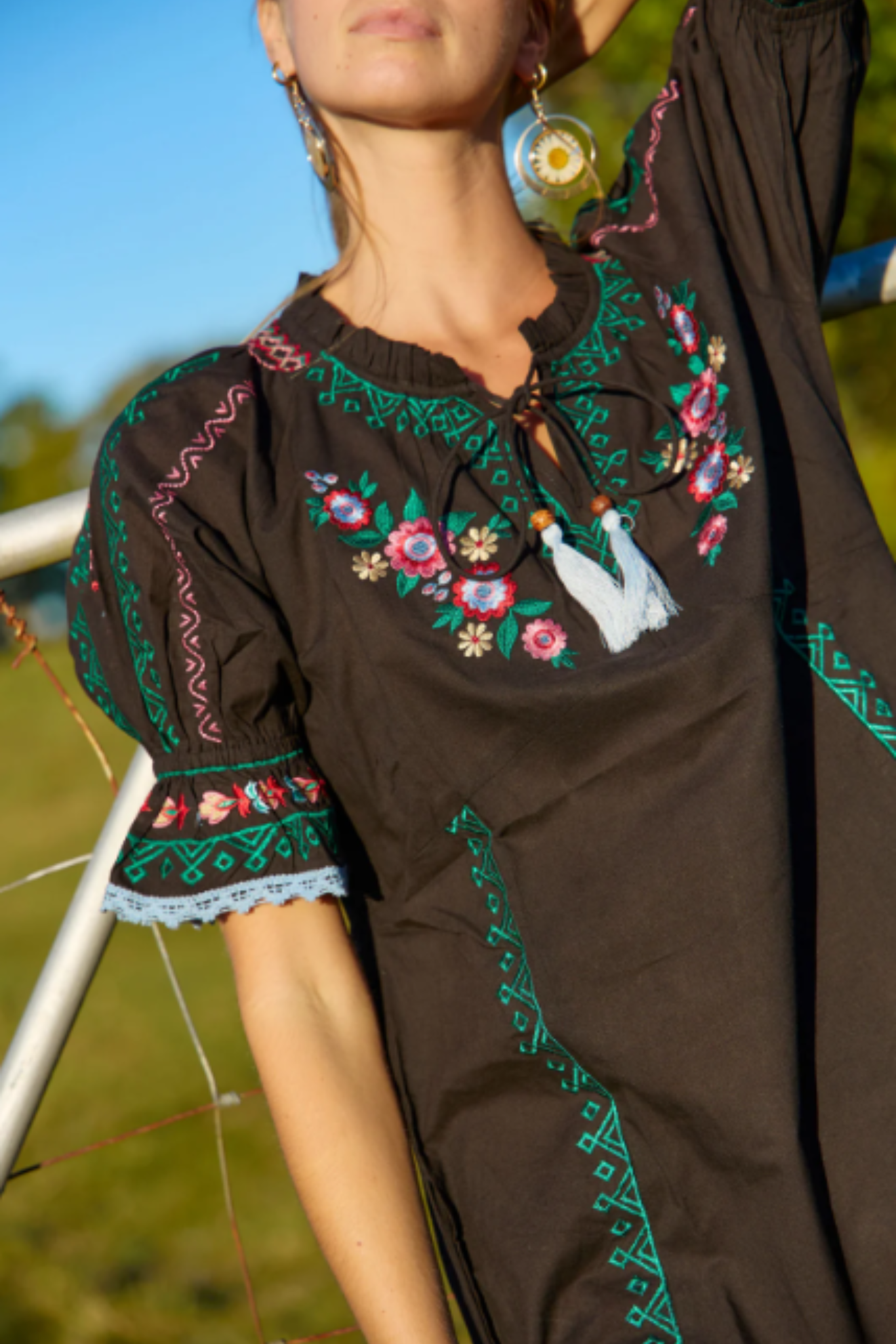 Spell Mini Dress by Solara Boheme featuring detailed floral embroidery on black fabric with bohemian style and tassel accents
