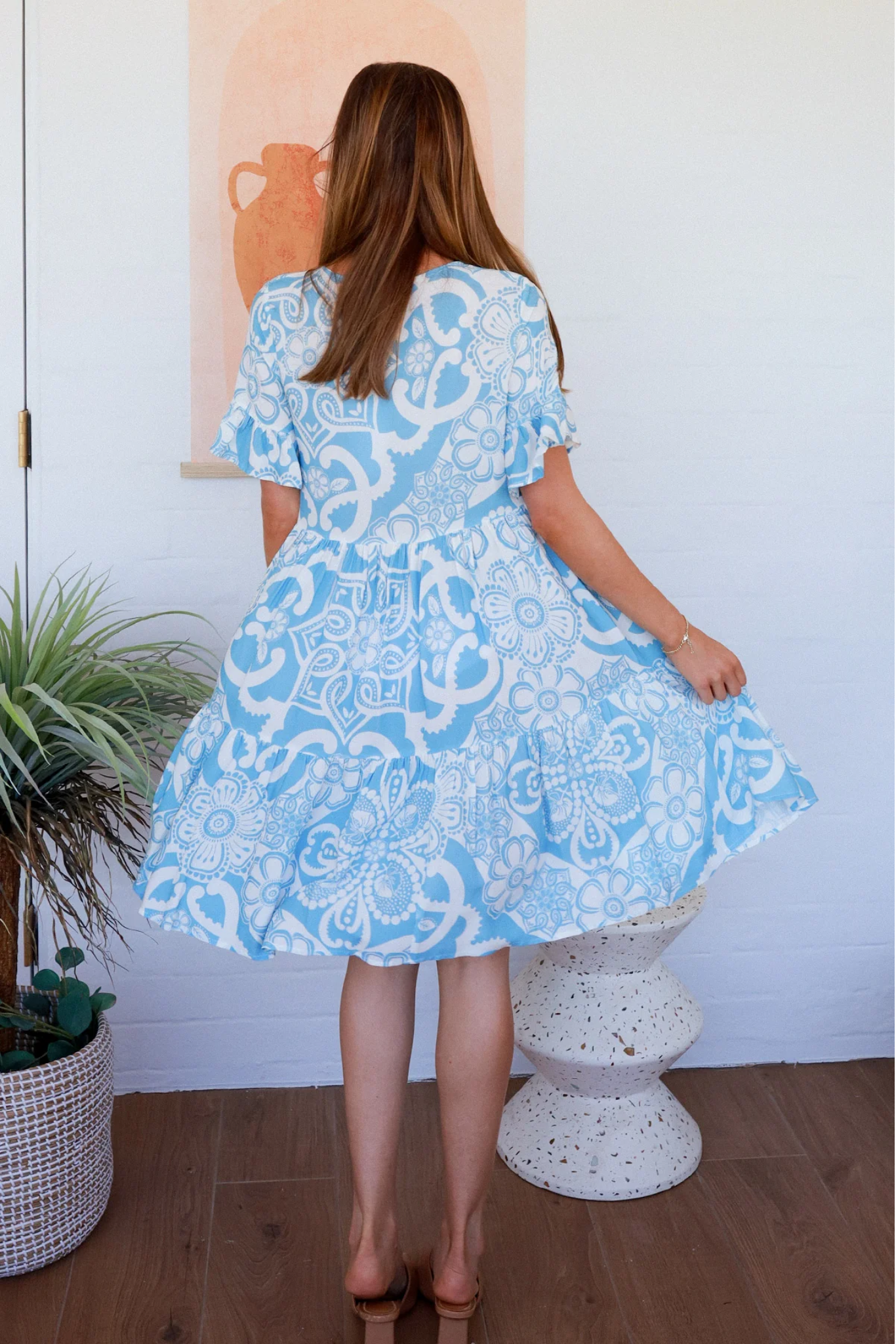 Back view of Stella Mini Dress by Solara Boheme featuring blue and white floral print with flutter sleeves and tiered skirt
