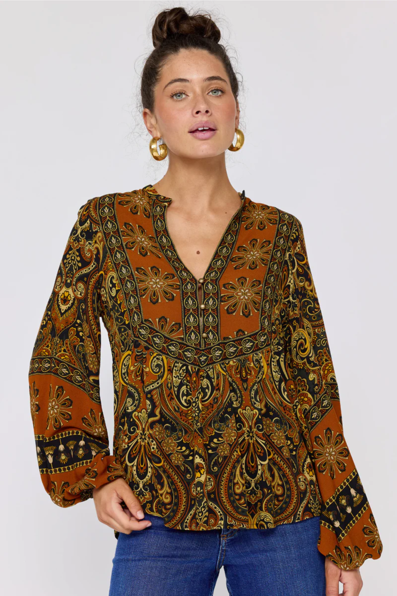 Woman wearing a patterned blouse with long sleeves on a white background