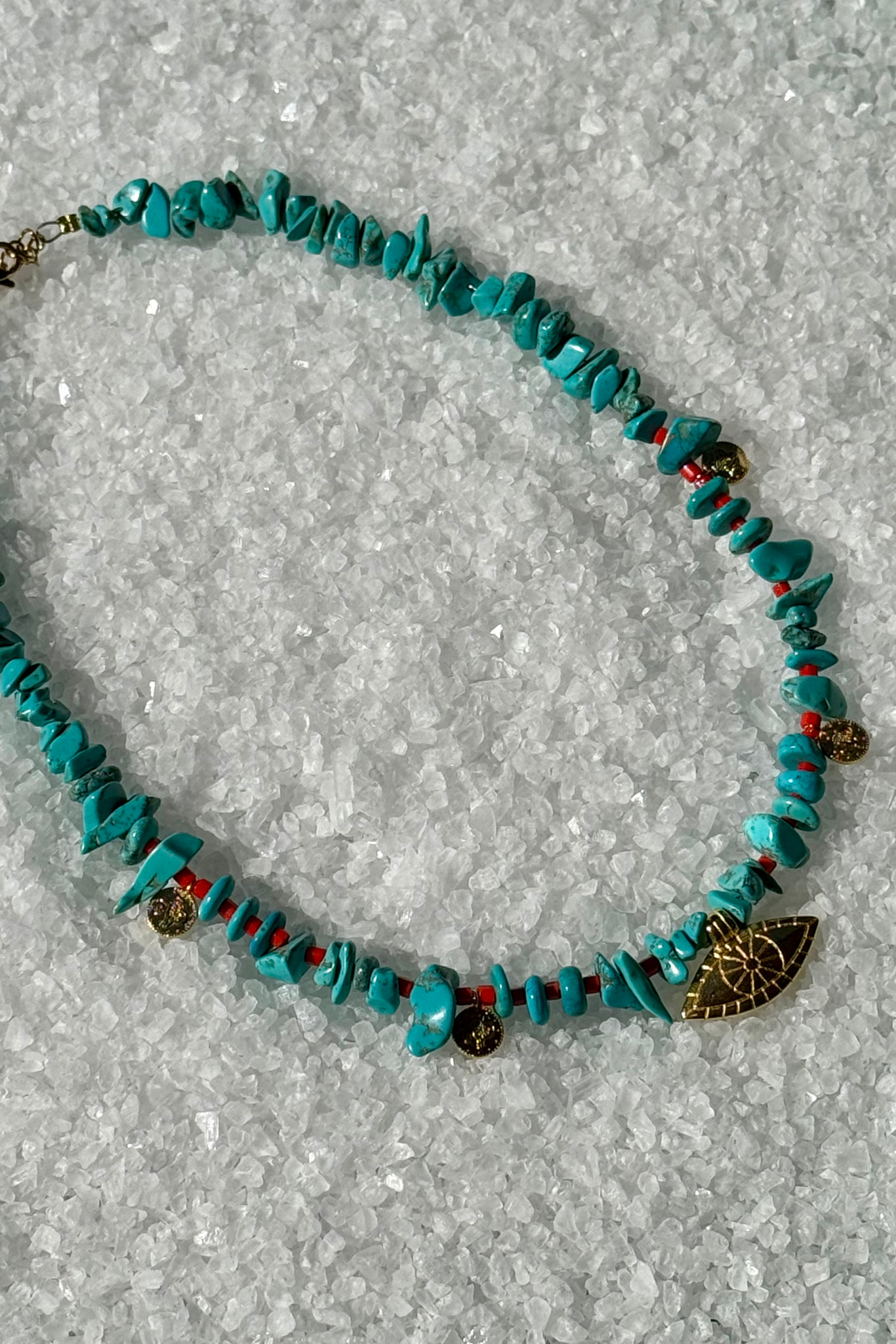 Turquoise beaded necklace with gold and red accents and evil eye charm