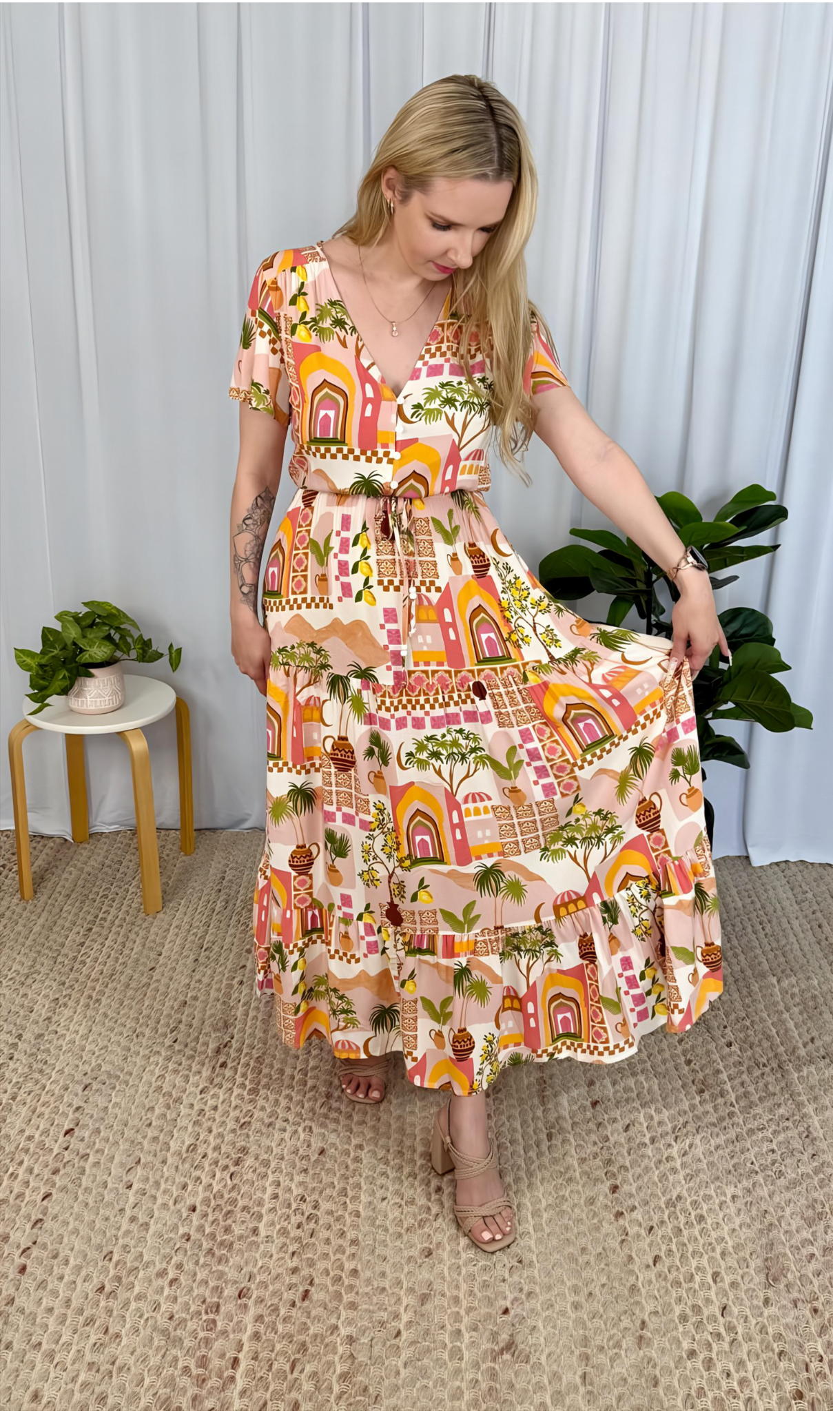 Woman wearing Yasmin Maxi Dress by Solara Boheme with vibrant sunset tones and tropical palm print in flowing tiered skirt