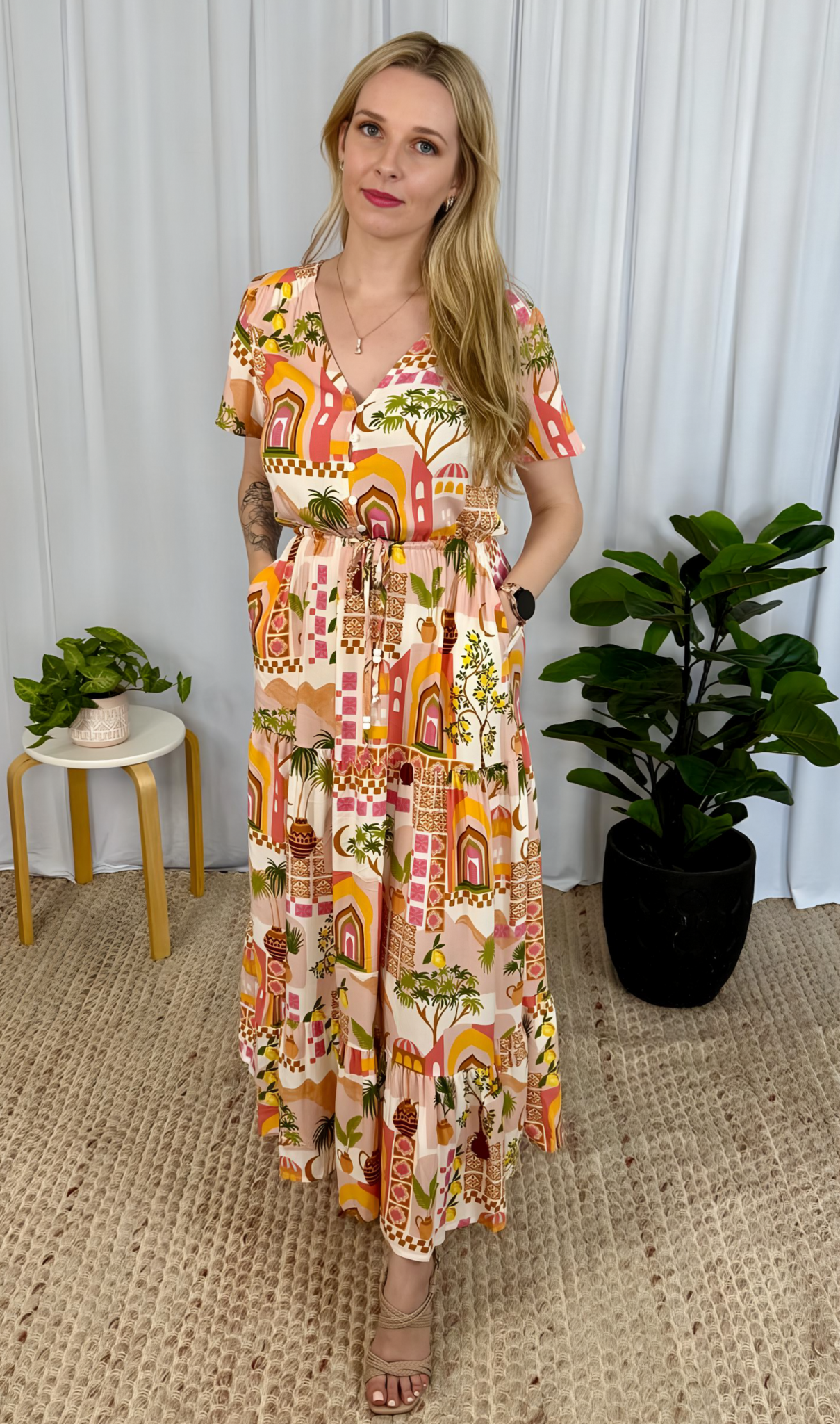Woman wearing Yasmin Maxi Dress by Solara Boheme with vibrant print, V neckline, button front, and drawstring waist in boho style